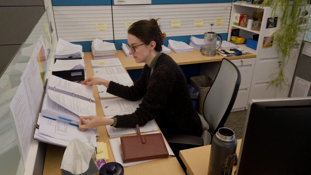 Policy services staff looking at binder of documents