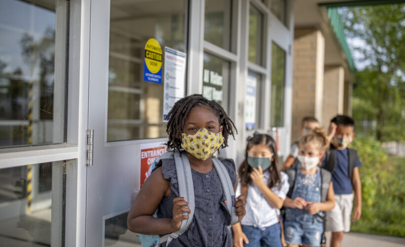 Diverse group of elementary school kids go back to school wearing masks